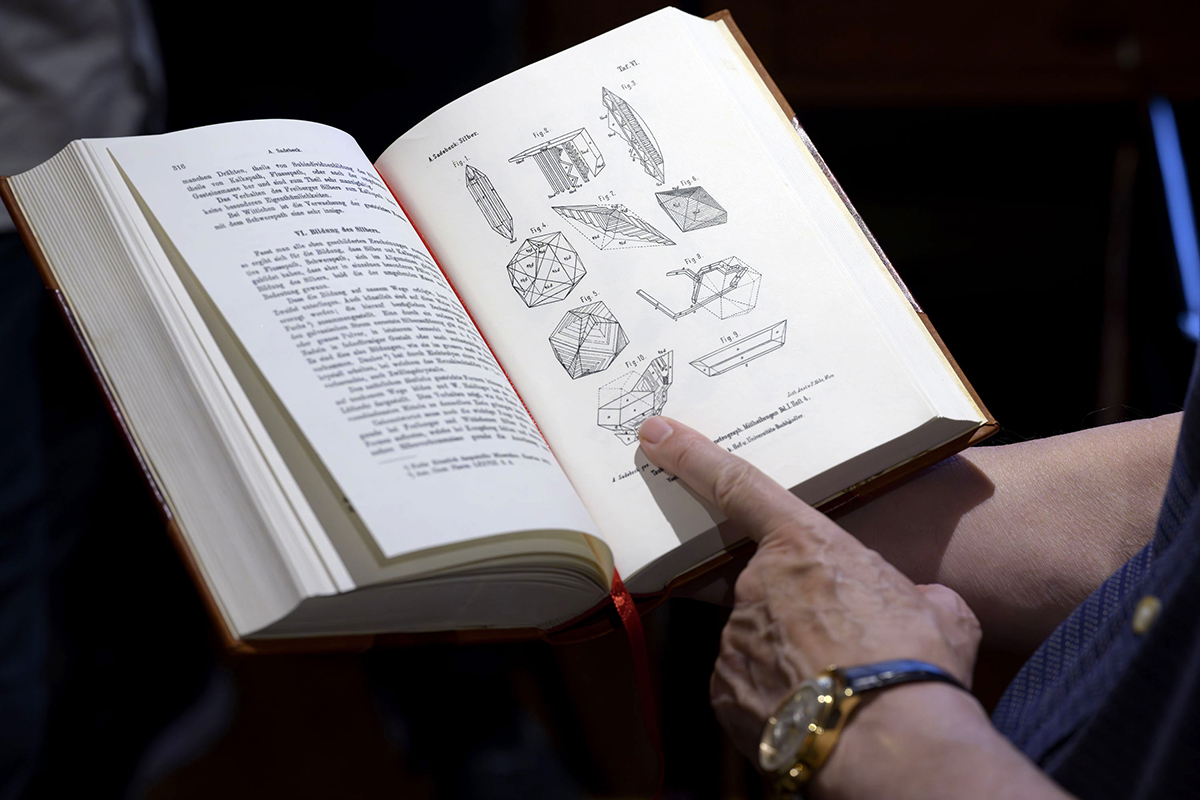 Joan Massagué points to a drawing of his silver crystal in the book Atlas der Krystallformen