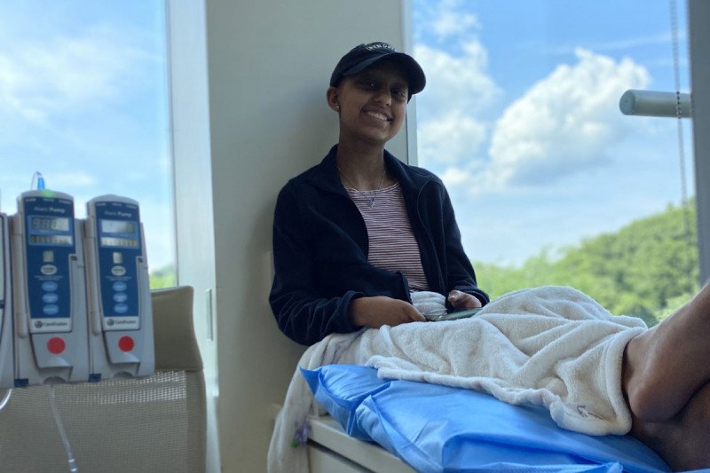 Sona sitting near a window, with medical equipment nearby