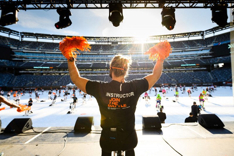 Woman with two pom poms on stage at the Cycle for Survival event at MetLife Stadium