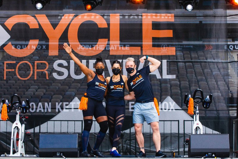 Three people on stage at the Cycle for Survival event at MetLife Stadium