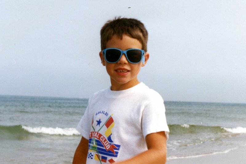 Young Ben wearing sunglasses at the beach.