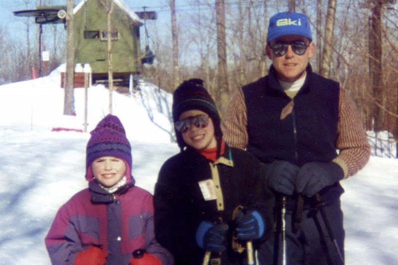 Two children with their dad, standing in snow.