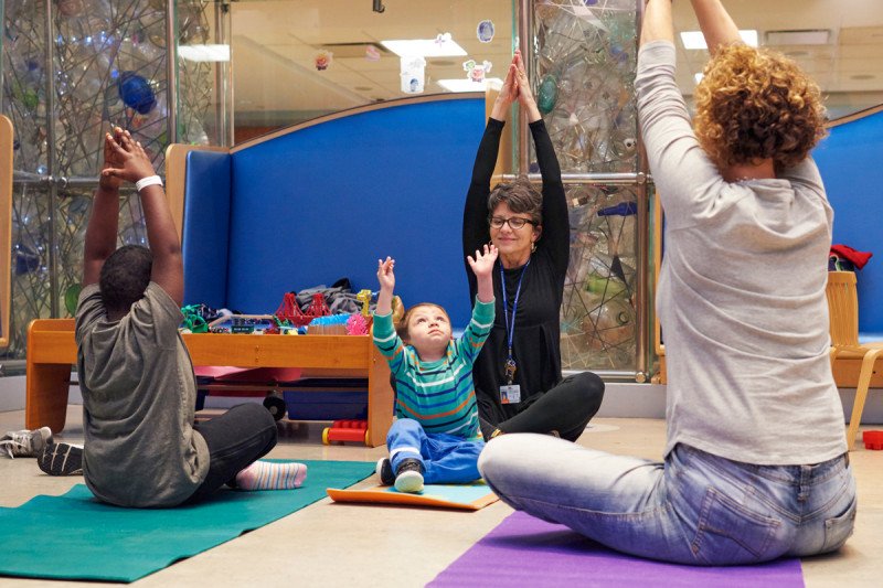 Children and their caregivers take part in pediatric yoga at Memorial Sloan Kettering.