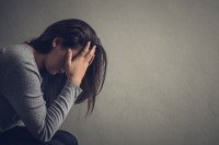 woman against grey background with her head in her hands