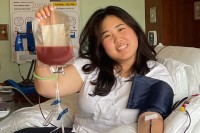 Grace Yang reclines in a hospital bed and holds a bag of stem cells.