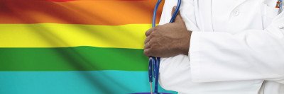 Doctor standing in front of a rainbow flag