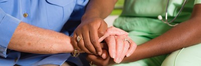 Closeup photograph of a nurse and patient holding hands