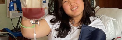 Grace Yang reclines in a hospital bed and holds a bag of stem cells.