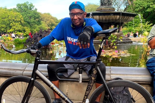 MSK patient Michael Simien poses with his bicycle in front of a fountain in New York City